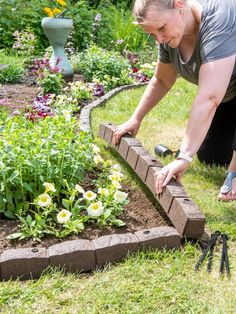 a woman kneeling down to plant flowers in her garden