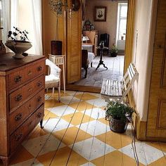 a room with yellow and white checkered flooring next to a wooden chest of drawers