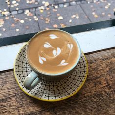 a cup of coffee sitting on top of a saucer next to a wooden table