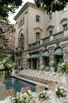 tables and chairs are set up in front of a large building with an outdoor swimming pool