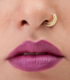 a close up of a woman's face with purple lipstick and gold nose ring