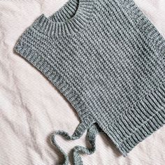 a knitted sweater laying on top of a bed