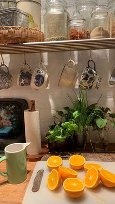 an image of oranges on a cutting board with coffee mugs and other kitchen utensils