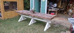 a wooden bench sitting in the grass next to a shed with a chicken cage on it