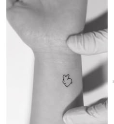 a small tattoo on the wrist of a person's left arm, with an outline of a bunny