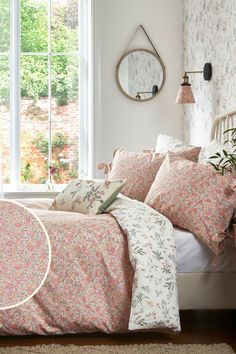 a bed in a bedroom with pink and white flowers on the comforter, pillows and pillow cases