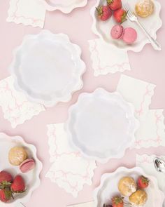 three plates with strawberries and pastries on them sitting on a pink tablecloth