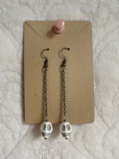 Handmade skull dangling earrings. I have seven available, all of them slightly vary in length from 2 3/4 inches - 3 inches. Skull beads are all unique with the line detail on the skull. Chain color is brass. Message me with any questions you might have!  Thanks for visiting my shop! Bone Color Dangle Earrings With Ear Wire, Nickel-free Bone Dangle Earrings, Nickel-free Bone-colored Dangle Earrings, Nickel Free Bone Color Dangle Earrings, Halloween Skull Print Skull Earrings, Bone Colored Metal Earrings For Pierced Ears, Adjustable Gothic Skull Earrings, Halloween Skull Jewelry With Ear Wire, Metal Skull Single Earring