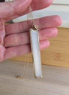 Selenite Necklace, Healing Stone, White Crystal Pendant, Gold Plated Selenite Pendant, Raw Natural Stone, Electroplated Gemstone, Long Bar **ABOUT THIS NECKLACE** **SEE MEASUREMENTS BELOW** This beautiful angelic stone pendant features a raw slice of selenite. This natural white bar is capped and rimmed around the edges in gold leaf. This pendant is two sided and features an organic, cloudy vertical pattern. Selenite comes from the Greek word Selene, which means moon. It is also known as a sweet White Quartz Minimalist Necklace, Minimalist White Quartz Crystal Necklace, Minimalist White Quartz Necklace, White Quartz Pendant Crystal Necklaces, White Quartz Pendant Necklace, White Quartz Necklace For Gift, White Crystal Necklace With Natural Stones As A Gift, White Crystal Necklace With Natural Stones For Gift, White Chalcedony Jewelry With Natural Stones