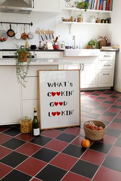 a kitchen with red and black tile flooring next to a sign that says what's cooking good i know