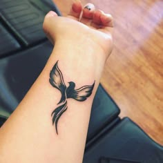 a small black bird tattoo on the wrist