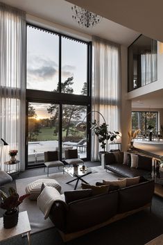 a living room filled with lots of furniture and large windows overlooking a field at sunset