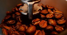 coffee beans being roasted in a blender with a small metal object sticking out of the top