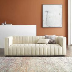 a living room with an orange wall and white furniture in the center, along with a rug on the floor