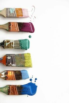 four paintbrushes with different colors of paint on them are lined up next to each other