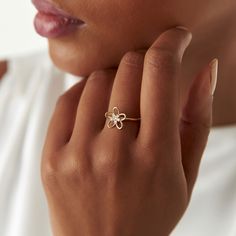 a close up of a person wearing a ring with a flower design on it's middle finger