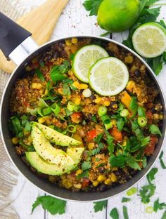 a skillet filled with vegetables and sliced limes