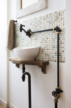 a white bowl sink sitting on top of a wooden shelf next to a faucet