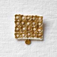 a white and gold square with flowers on the top is sitting next to a coin