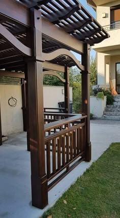 a wooden gazebo sitting on top of a lush green field next to a building