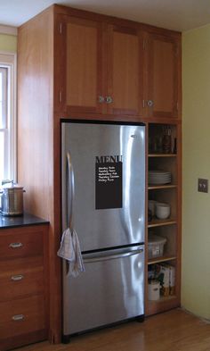 a stainless steel refrigerator sitting in a kitchen next to wooden cabinets and cupboards with magnets on it