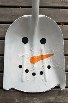 a metal snowman with an orange nose and black eyes