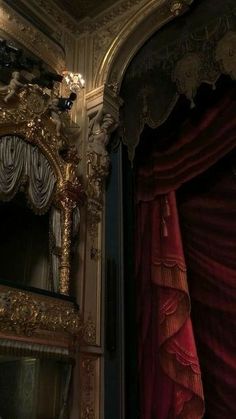 an ornately decorated room with red curtains and gold trimmings, including a mirror