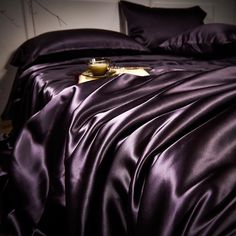 a bed covered in purple sheets and pillows