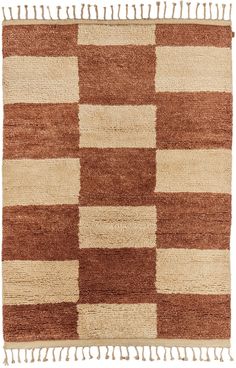 a brown and white checkered rug with fringes on the bottom, in front of a