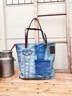 a blue jean purse sitting on top of a wooden table next to a metal bucket