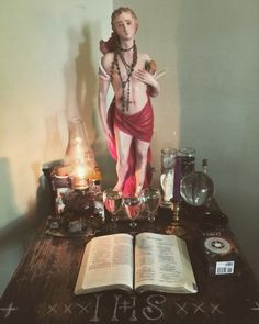 a statue of a woman holding a candle on top of a table with an open book