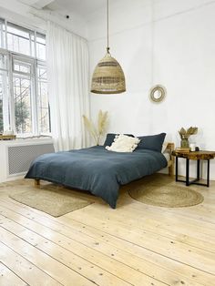 a bed sitting on top of a hard wood floor next to a window in a bedroom