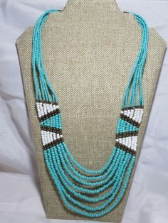 A simple but intricate beaded necklace....all done in a "tribal" Southwestern pattern...seven strands in all turquoise, white and antiqued gold tone beads glass and metal....necklace measures 24" total length by 8" across the BIB section...length around your neck is 20" but you can get an extra 2" with the extension chain. In great shape. Unique Turquoise Beaded Necklaces With Dangling Beads, Hand-strung Multi-strand Bohemian Turquoise Necklace, Turquoise Multi-strand Beaded Necklace For Festivals, Bohemian Multi-strand Hand-strung Turquoise Necklace, Southwestern Multi-strand Turquoise Beads, Bohemian Multi-strand Turquoise Necklace With Large Beads, Unique Turquoise Multi-strand Beaded Necklaces, Turquoise Multi-strand Bohemian Beads, Bohemian Multi-strand Beaded Turquoise Necklace