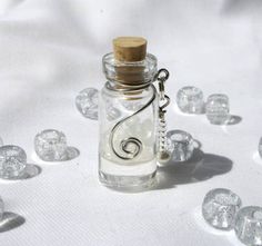 a glass bottle with a cork top on a white surface surrounded by crystal stones and tiny hearts