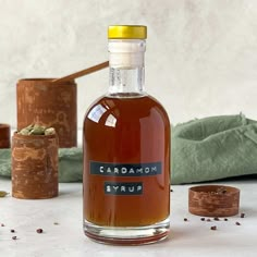 a bottle of cardamoa syrup sitting on a table next to some wood slices