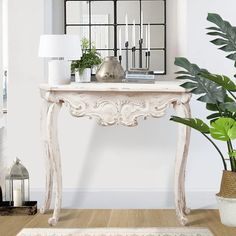 a white console table sitting next to a potted plant