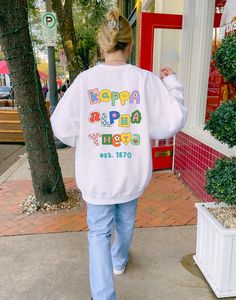 a woman is walking down the sidewalk wearing a sweatshirt that says happy birthday on it