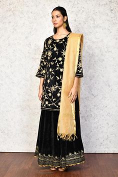 Black kurta with contrast floral embroidery. Paired with a lehenga, highlighted with floral embroidered hem. Comes along with a dupatta.
Components: 3
Pattern: Embroidery
Type Of Work: Floral
Neckline: Round Neck
Sleeve Type: Three Quarter Sleeves
Fabric: Kurta and Lehenga: Velvet, Dupatta: Chanderi, Lining: Shantoon
Color: Black
Other Details: 
Length:
Kurta: 36 inches
Lehenga: 40 inches
Occasion: Mehendi and Haldi - Aza Fashions Black Semi-stitched Embroidered Fabric, Black Sharara For Festive Occasions, Festive Embroidered Black Sharara, Traditional Black Sharara For Transitional Seasons, Black Embroidered Sharara For Transitional Season, Embroidered Black Sharara For Transitional Seasons, Traditional Black Sets With Floral Embroidery, Transitional Black Embroidered Sharara, Festive Black Floral Embroidered Sets