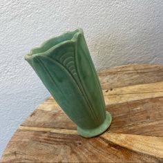 a green vase sitting on top of a wooden table