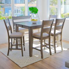 a dining room table with four chairs and a potted plant on top of it