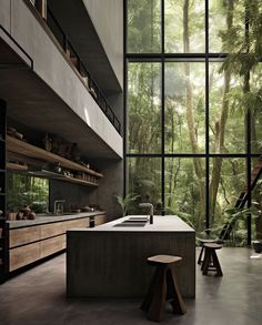 an open kitchen with lots of windows and plants in the backround, along with stools