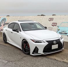 a white car parked in front of a wall with graffiti