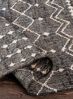 an area rug on top of a wooden floor with a black and white patterned design