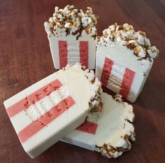 four pieces of cake with white frosting and red stripes on them sitting on a wooden table