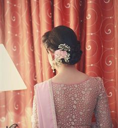 the back of a woman's head wearing a pink sari with flowers in her hair