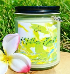 a jar of candle sitting on top of a wooden table next to a white flower