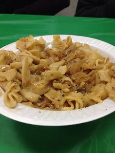 a white plate topped with pasta and sauce on top of a green tablecloth covered table