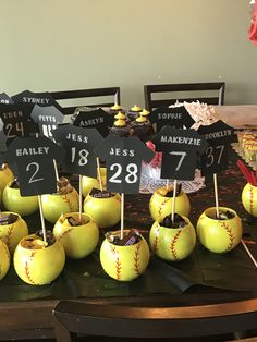 a table topped with lots of green apples covered in baseball balls and numbers on top of them