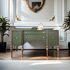 a room with a green dresser, mirror and potted plants on the sideboard