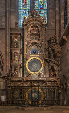 the inside of a church with stained glass windows and an ornate clock on it's side